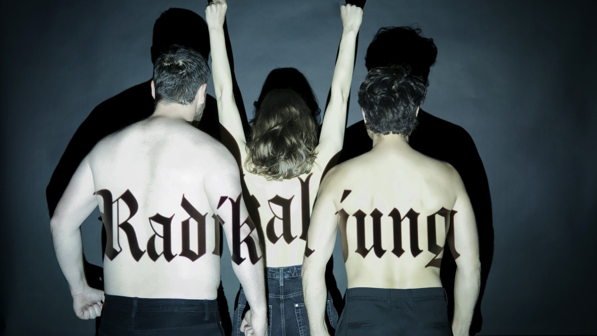 Drei Personen stehen mit nacktem Rücken zur Kamera, eine reißt die Arme nach oben und auf ihrer Haut steht der Schriftzug "Radikal jung". | © Sarah Kralisch