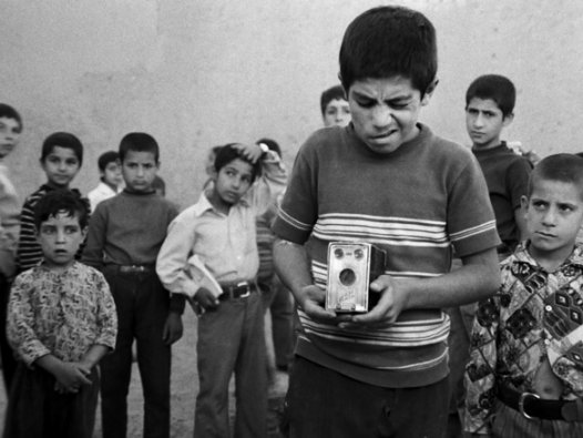Auf dem Schwarz-Weiß-Foto sind mehrere Kinder zu sehen, im Vordergrund ein Junge, der einen Fotoapparat in den Händen hält und im Begriff ist, ein Foto zu schießen. | © Arsenal